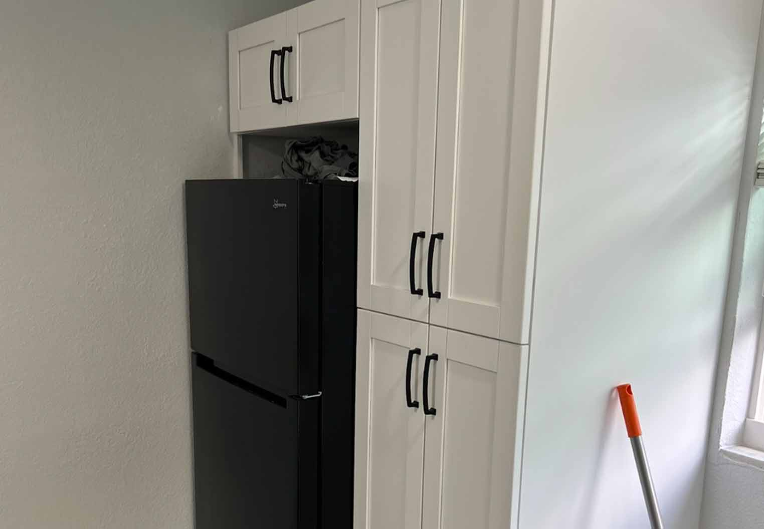 Custom white cabinats build around a black fridge