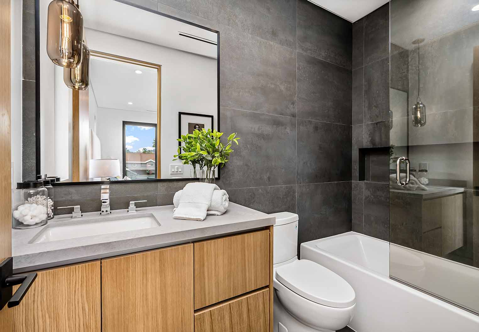 contemporary bathroom with dark stone walls and lite wood cabinatry