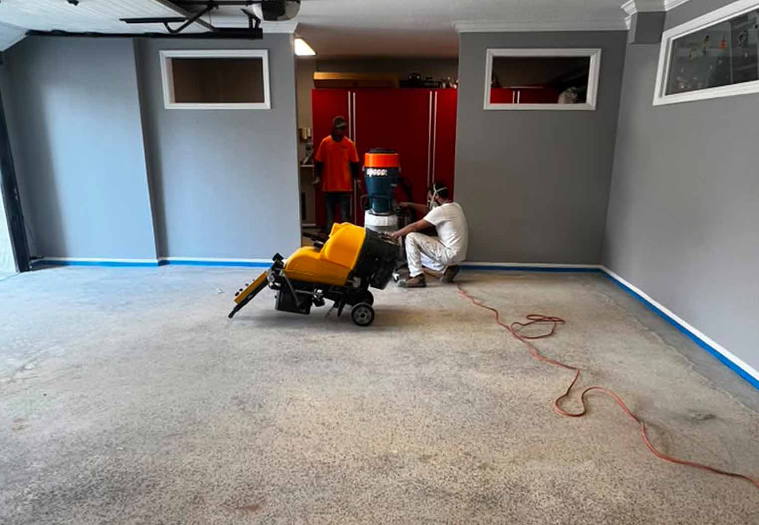 two workers preparing a floor for epoxy flooring installation