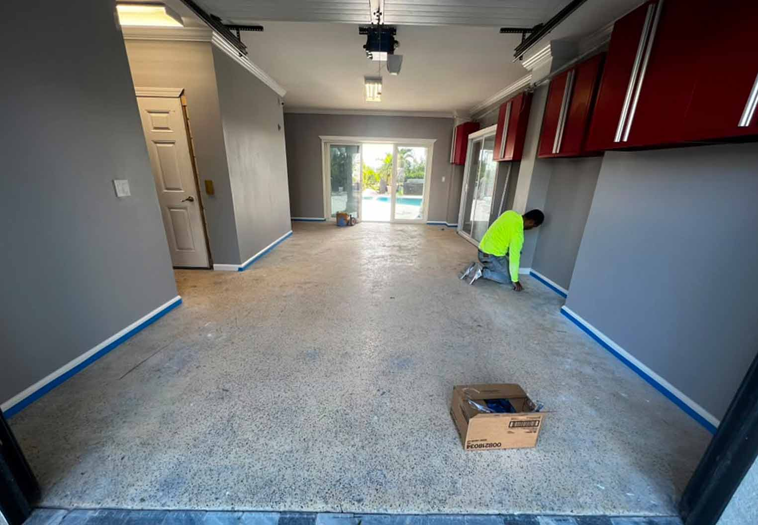 worker taping off perimmiter of floor before epoxy installation