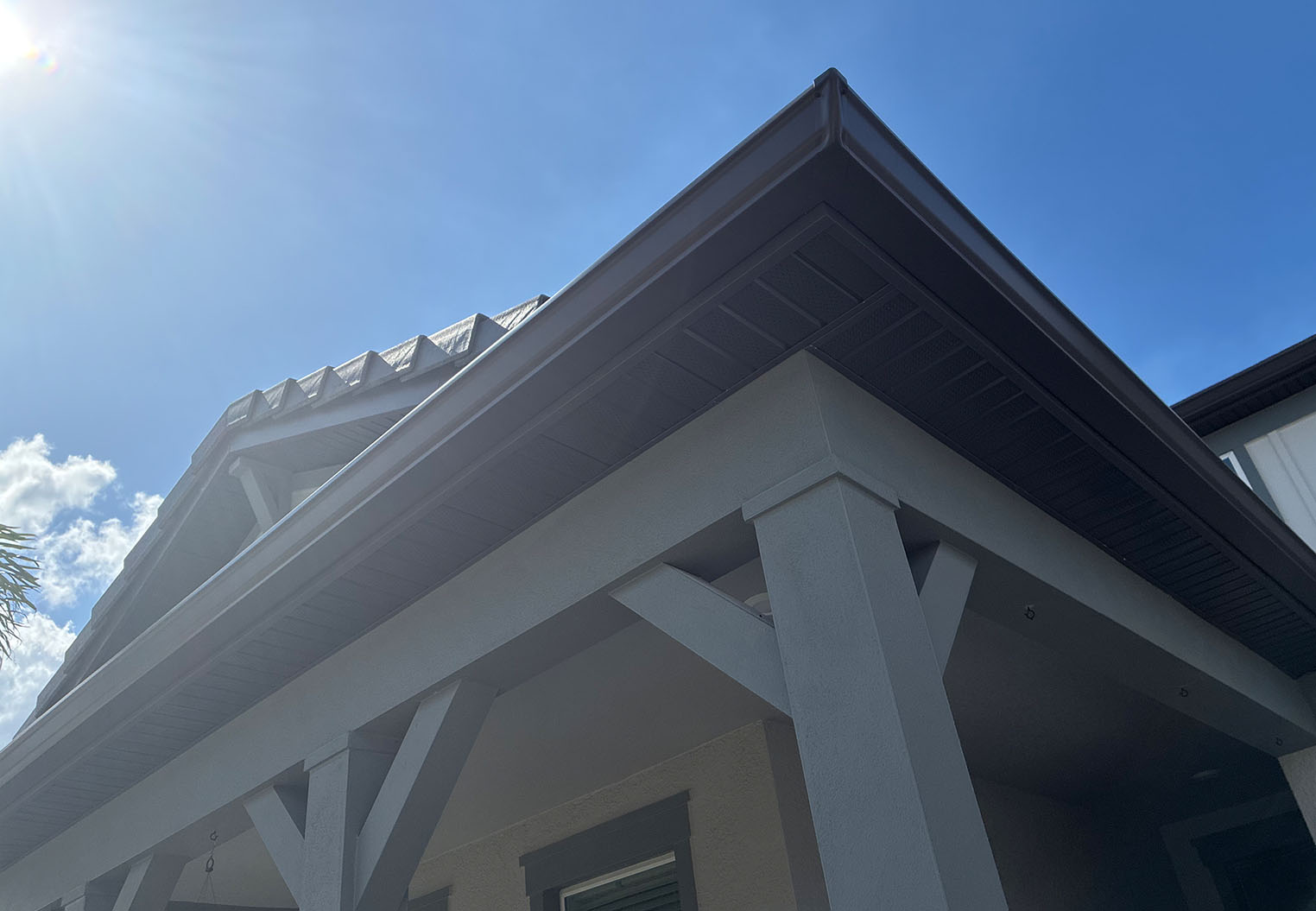 close of of residential roofline corner with dark colored soffit and matching gutters