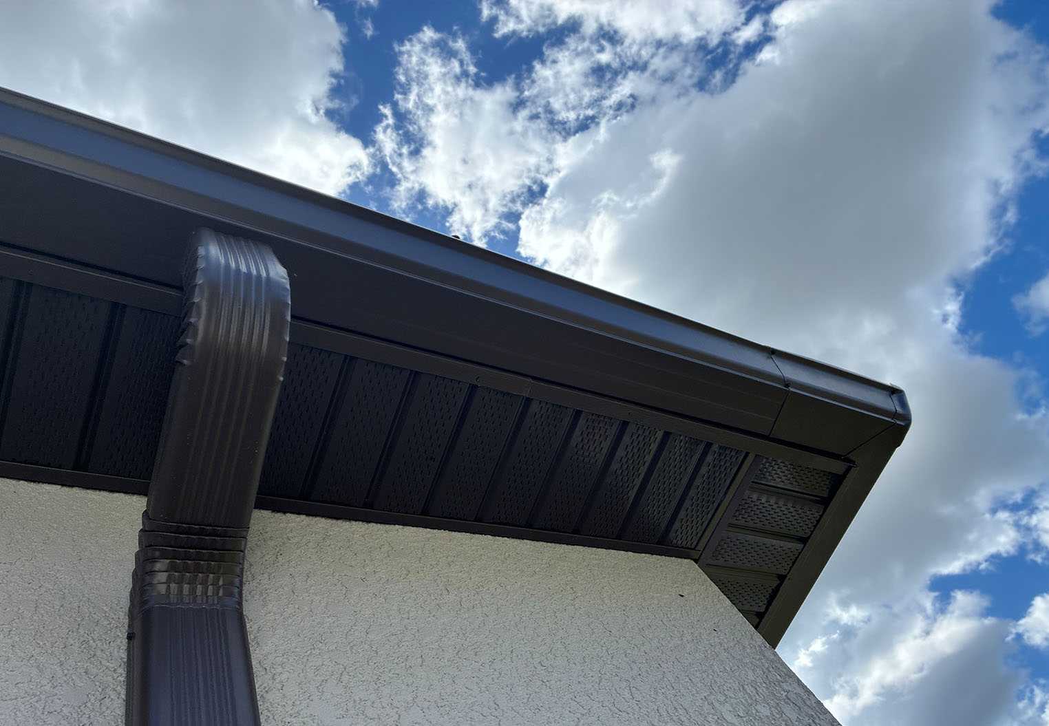 close up of new dark colored soffit with matching gutter and downspout